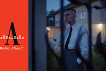 A man smokes a cigar outside a house.