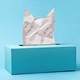A tissue box with a tissue in it shaped as the silhouette of a cat
