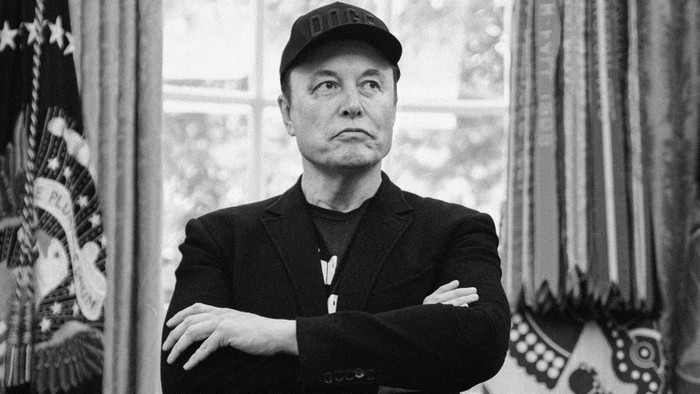Elon Musk stands with his arms crossed