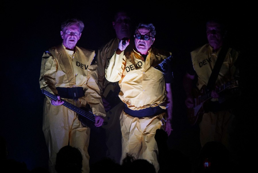 Four musicians wearing yellow costumes perform onstage.
