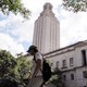 A student walks in front of a clock tower at UT Austin