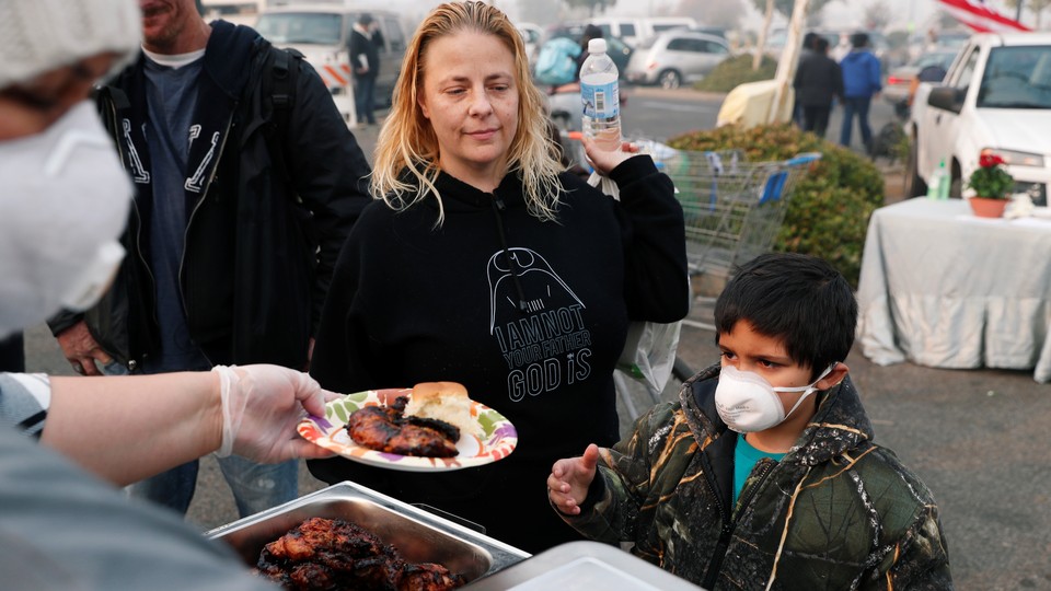 After losing their home in Magalia, California, in the Camp Fire, Robin Tompkins and her son, Lukas, line up for a free meal at a makeshift evacuation center in Chico, California, on November 16, 2018.