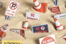 Traffic cones and "Private Property" and "No Trespassing" signs scattered in sand