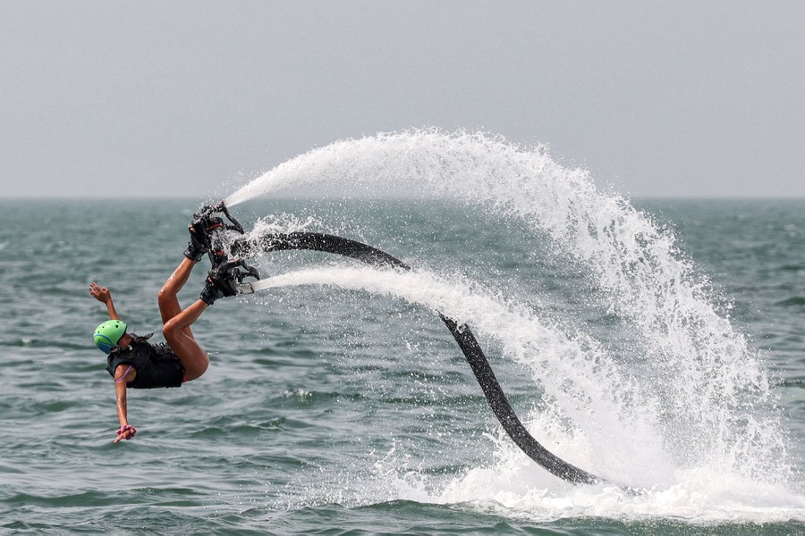 A person falls into water while wearing a device on their feet that blasts water jets downward.