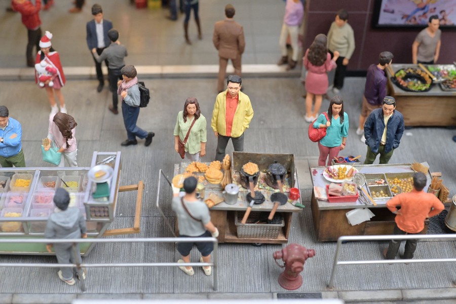 A re-created street scene featuring models of pedestrians and food vendors