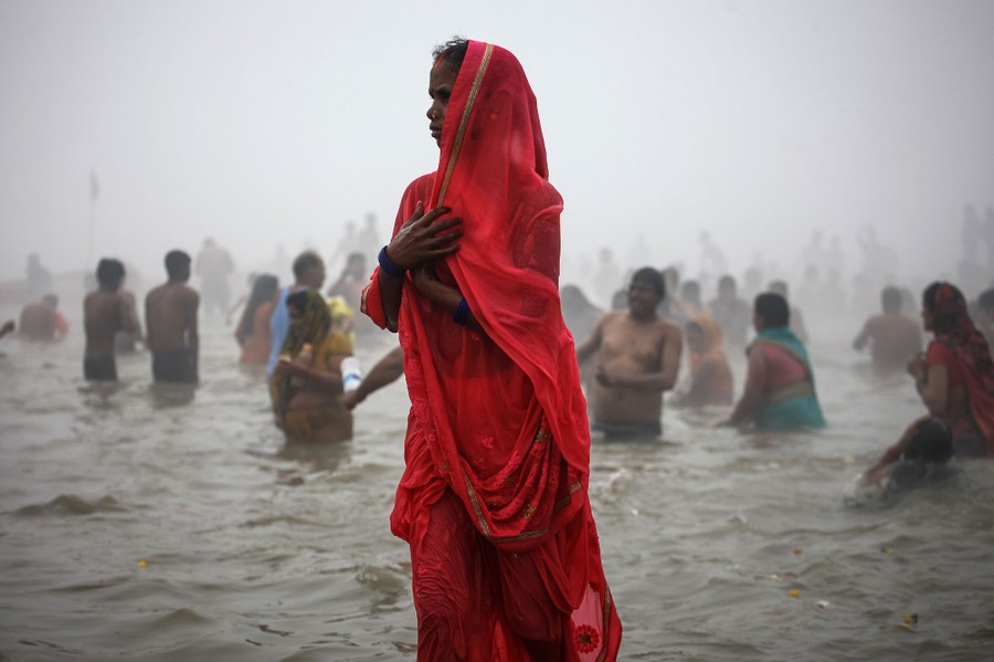 Dozens of people are seen wading in river water.