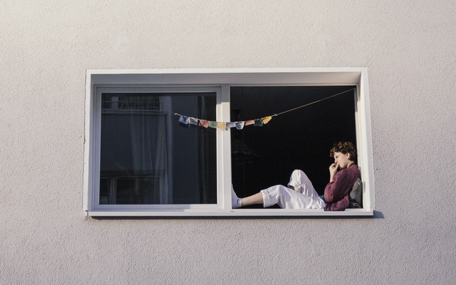 A woman lounges in the window of an apartment building