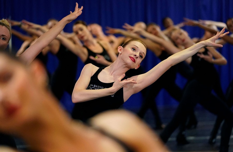 Several dancers raise their arms during a rehearsal.