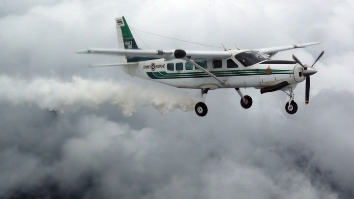 A plane flying through clouds and emitting a vapor