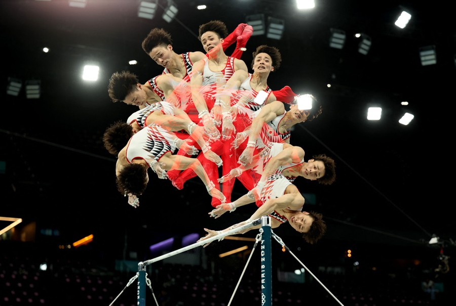 A multiple-exposure picture of a gymnast flipping over the top of a high bar