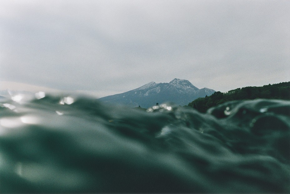 photo of ocean surface waves and mountain behind