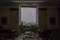 A photograph of a bombed-out room with sandbags piled behind a glassless window