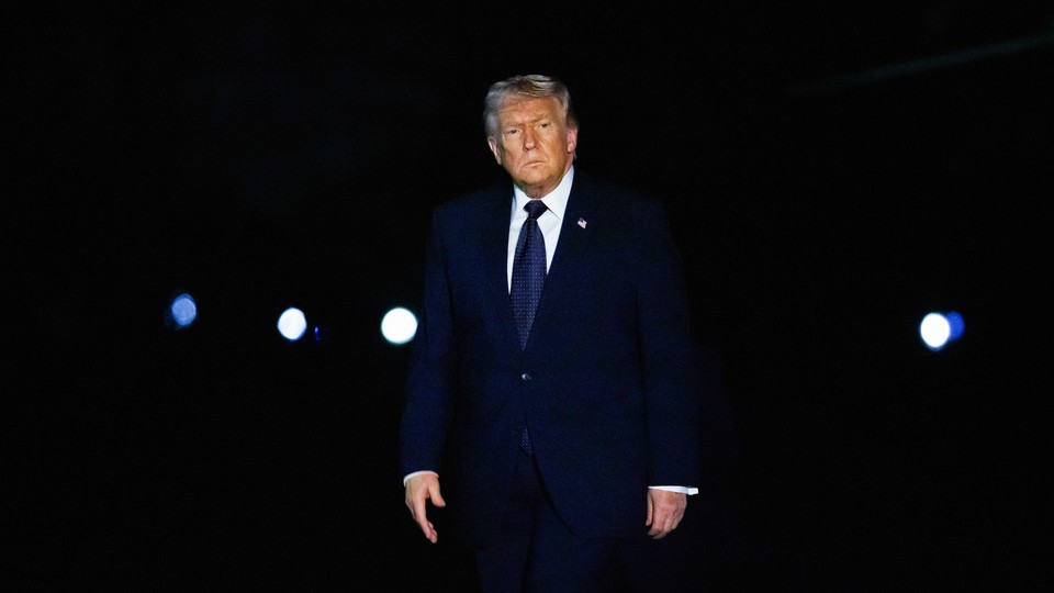 A photograph of Trump in a blue suit against a dark background