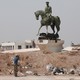 A Kurdish fighter fires a weapon at a statue of Bassel al-Assad, Bashar al-Assad's brother, in Hasaka, Syria, in August 2016.