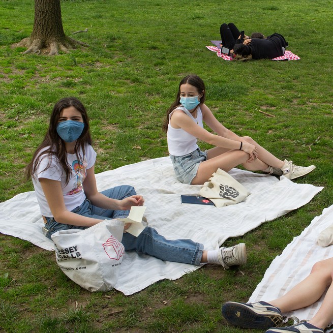  teenagers wearing masks sit apart on picnic blankets.