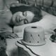 A black-and-white image of a woman sleeping next to a sound conditioner