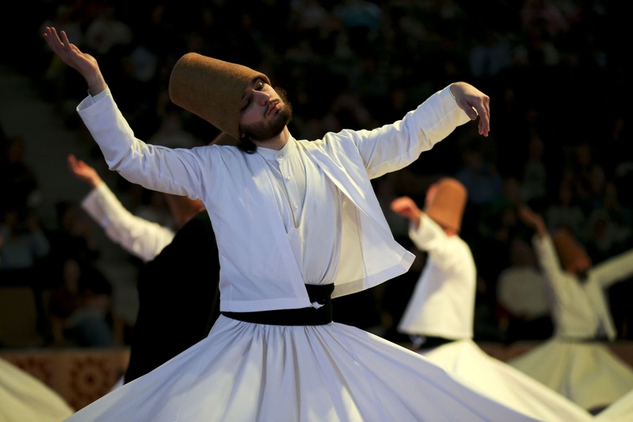Men in traditional costumes spin and dance during a ceremony.