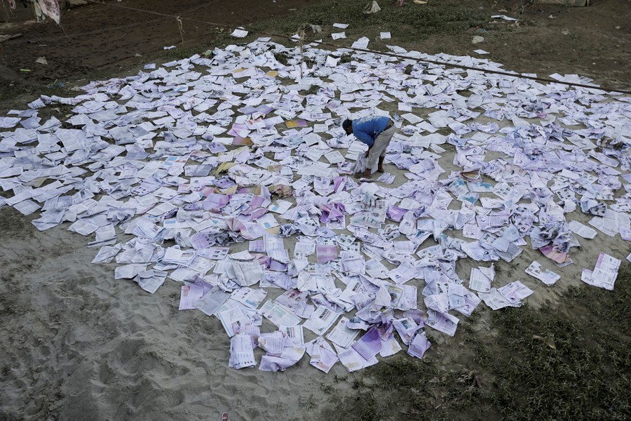 A person leans over, surrounded by many opened books that have been laid out to dry.