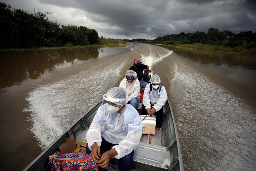 Several health-care workers ride in a small motorboat.