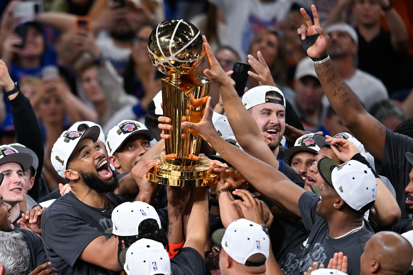 Members of the New York Knicks celebrate with a trophy on the court after winning the NBA Finals.