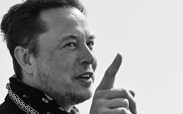 A black-and-white photo of Elon Musk with a bandana around his neck