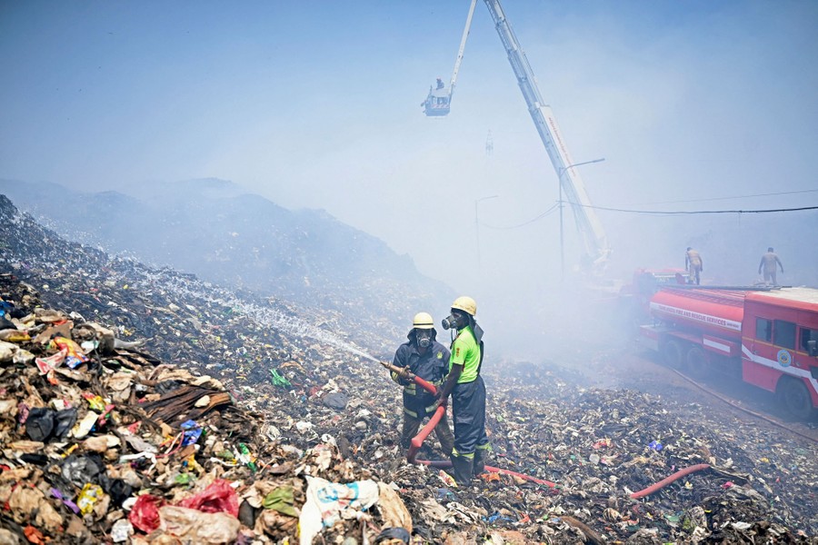 Firefighters try to extinguish burning garbage on a huge landfill.