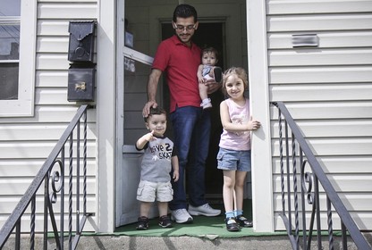 Mohammad Zkrit and three of his four children stand on the porch of their newly-rented home in Erie, Pennsylvania. The family fled the ongoing civil war in Syria and have been resettled in the United States.