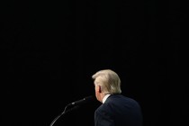 photo of Donald Trump's back at a microphone surrounded by black