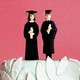 A wedding-cake topper with two people in graduation gowns