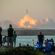 Spectators watch as SpaceX's Starship lifts off in a cloud of fire and smoke from the Gulf Coast