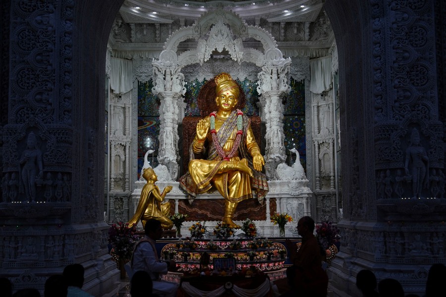 People take part in a ritual in front of a golden statue.