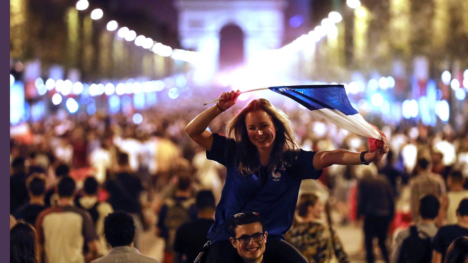People celebrate on the Champs-Élysées, with the Arc de Triomphe in the background, after the semifinal match between France and Belgium at the 2018 World Cup