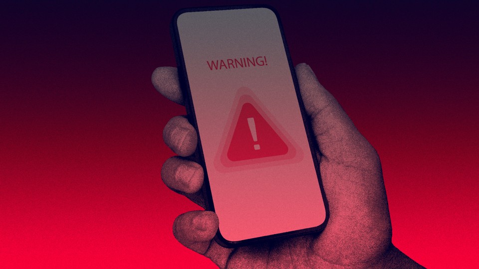 A hand holding a phone with a warning blaring on its screen