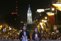 Two teens look at a television screen during Pope Francis's 2015 visit to Philadelphia.