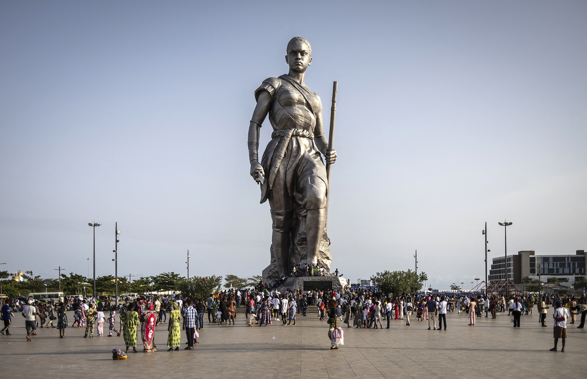People gather around the base of a tall statue of an Amazon warrior.