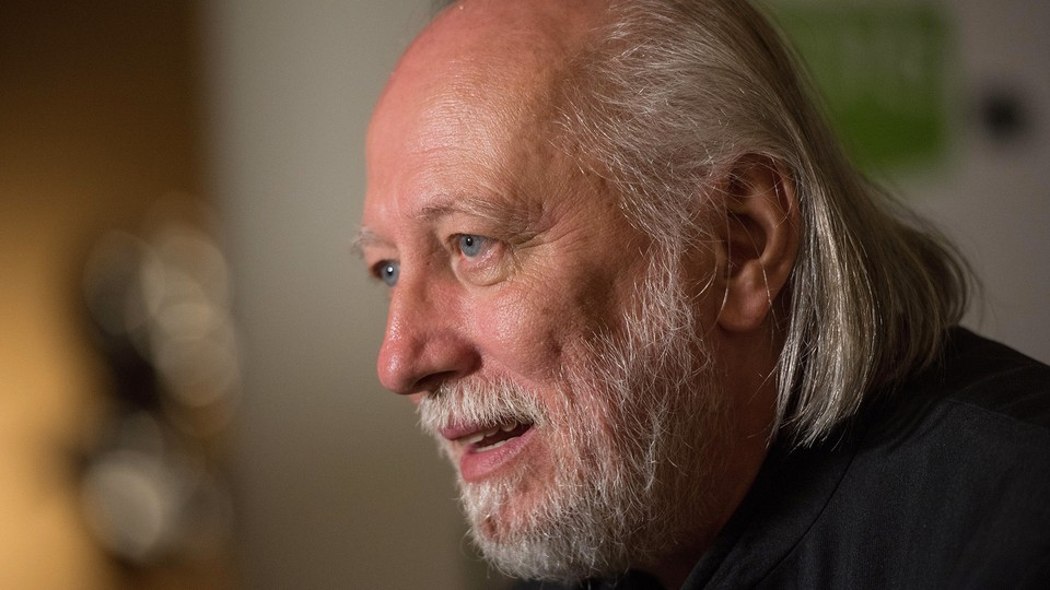 Photograph, in profile, of an older, balding man with a beard and chin-length gray hair.