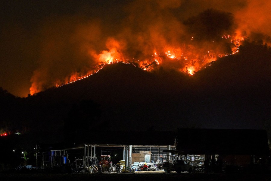 A wildfire burns across hillsides at night.