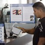 A traveler scans his fingerprints at the Houston airport as a customs officer monitors his computer.