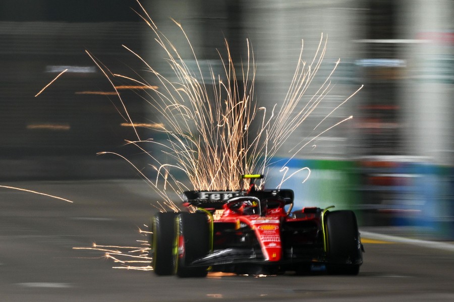 Sparks fly behind a passing F1 race car.