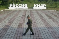 A guard walks along a platform past signs, which read "Russia" and "DPRK."