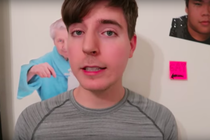 A boy looking into a camera with posters on the wall behind him