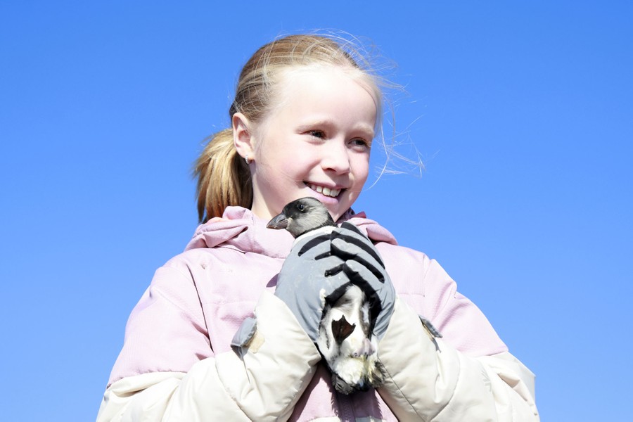 A young person smiles while holding a small bird.