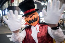 A person wearing a pumpkin-masked Halloween costume poses for the camera.