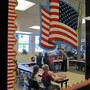 The photograph peers into an elementary school classroom through a door with an American flag sticker on it. 