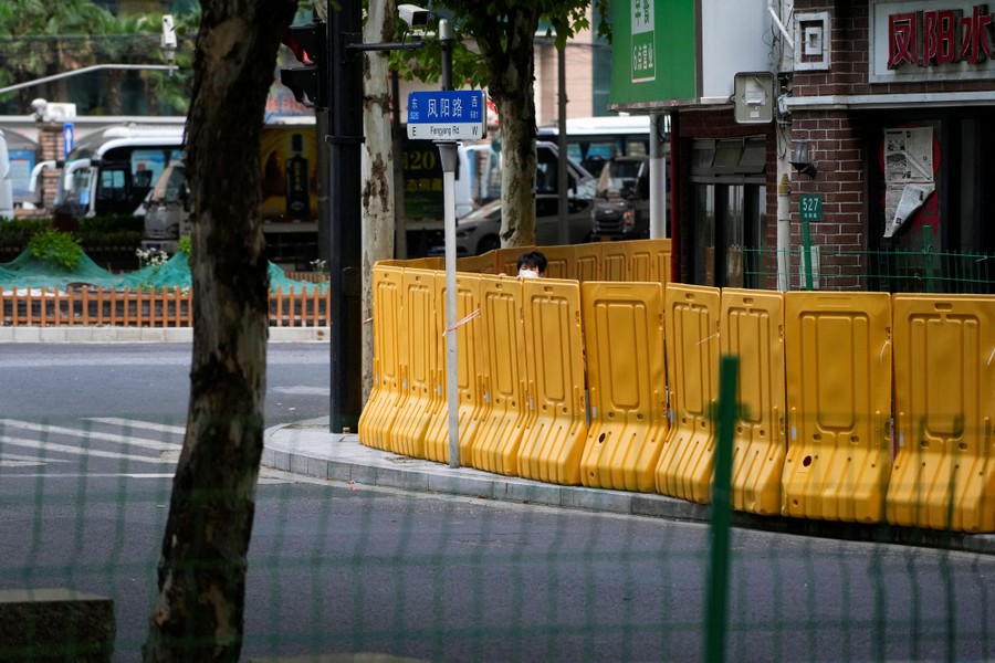 A resident peers over a temporary plastic wall on a city sidewalk.