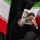 A photo of an Iranian holding a flyer picturing two supreme leaders
