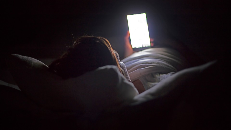 A woman looks at her phone in the dark