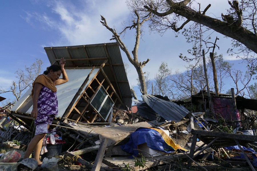 A person walks through debris left by a storm among destroyed buildings.