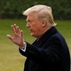 President Trump raises his hand toward a camera.