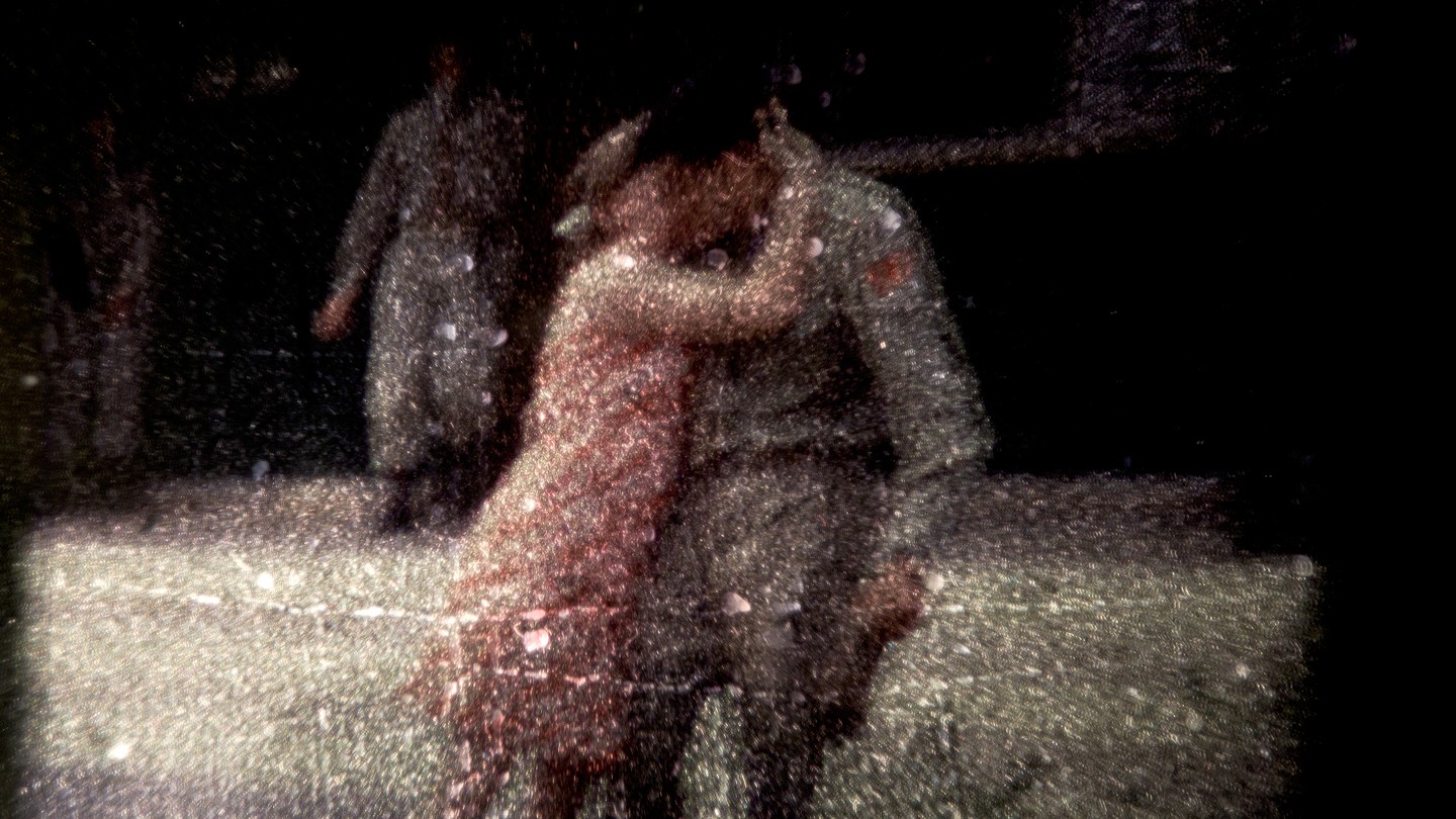 A manipulated image with scratches and dust shows two people kissing in a street